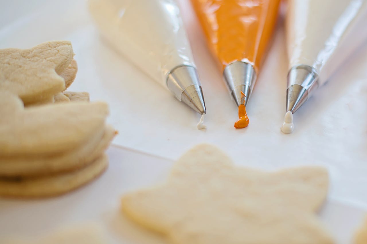 Three piping bags filled with colorful icing for decorating cookies on a white surface.