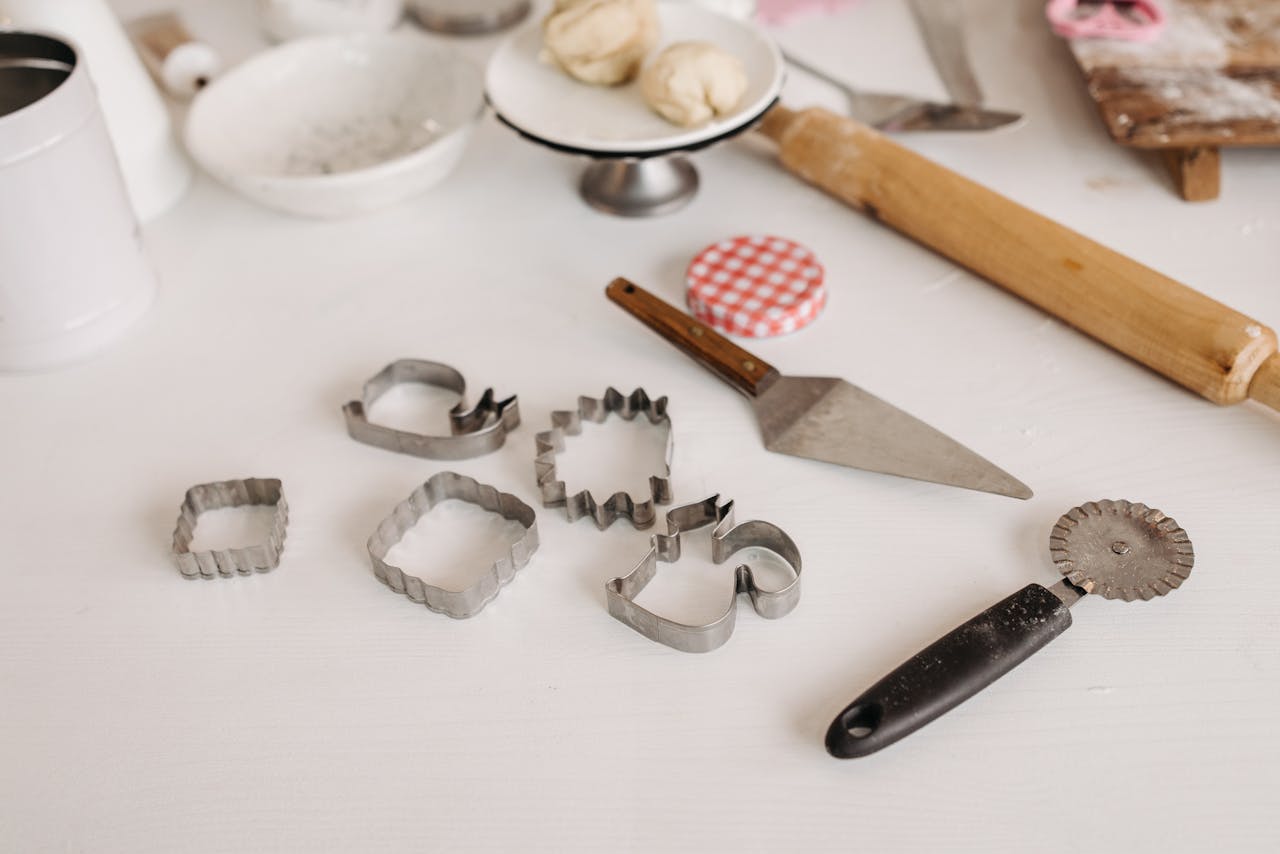 Selection of baking tools with cookie cutters and dough on a white surface, perfect for creative baking.